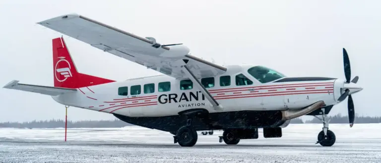 A Grant Aviation turboprop plane parked on a snowy winter runway in Alaska